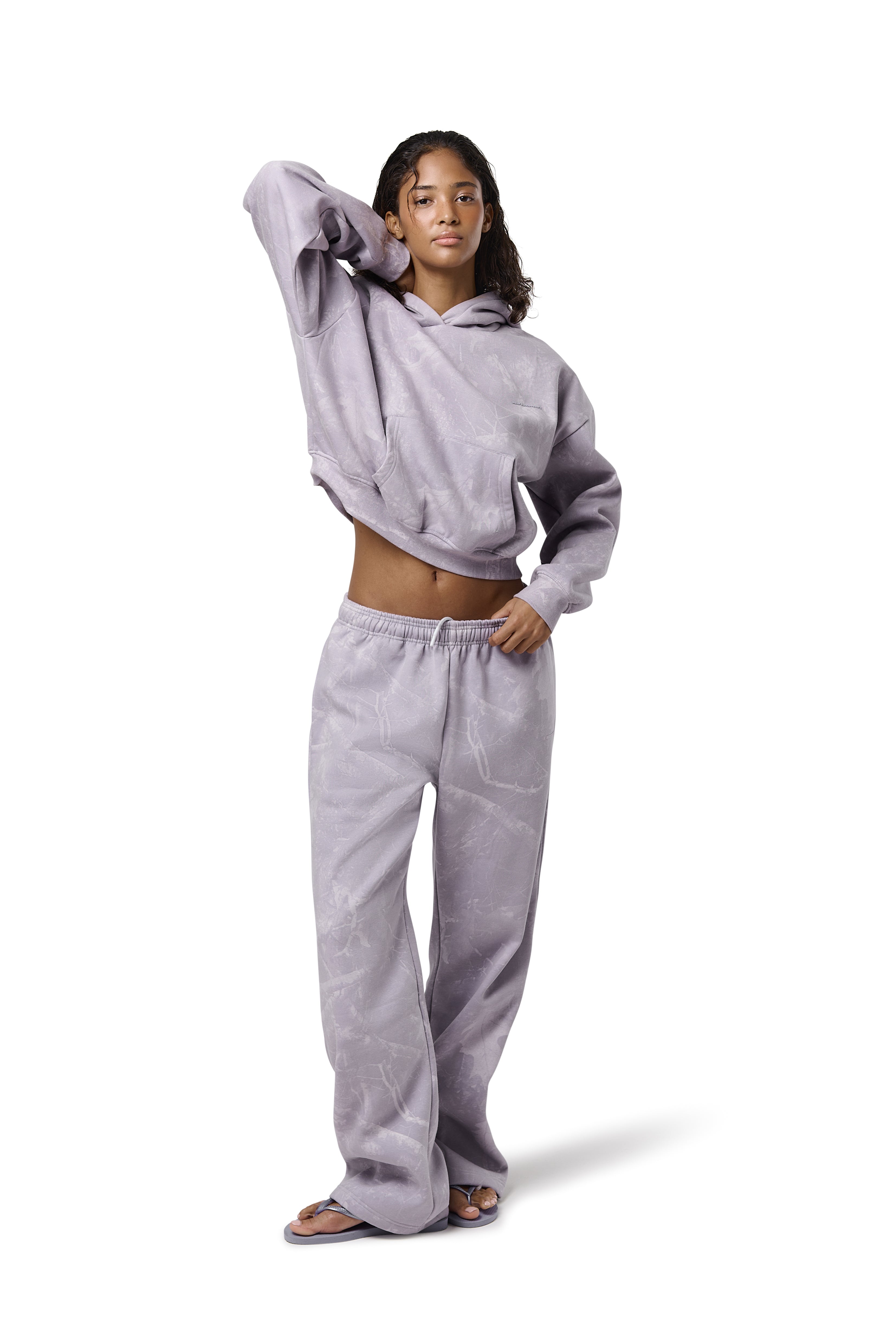 Lilac high-waisted straight-leg sweatpants with subtle twig camo print, elasticated drawstring waist, and embroidered Sisters & Seekers logo. Soft cotton-blend fabric in sizes 2XS–3X, available in Petite, Regular, and Tall lengths